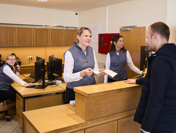 Freundliche Mitarnbeiter kümmern sich an der Rezeption um Anliegen eines Gastes.