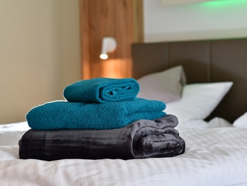 Handtücher vom Landhotel Hermannshöhe auf dem Bett eine Hotelzimmers.