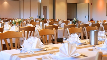 Hochzeitssaal mit gedeckten Tischen und schöner Dekoration.