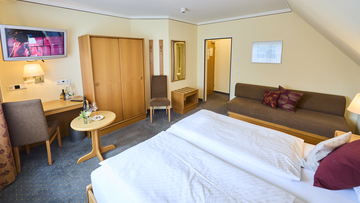 Hotelzimmer mit Doppelbett und Sofa.